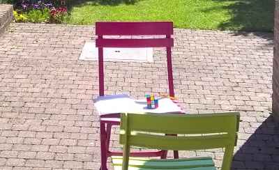 garden with 2 chairs, one having a notebook and a rubik's cube on it